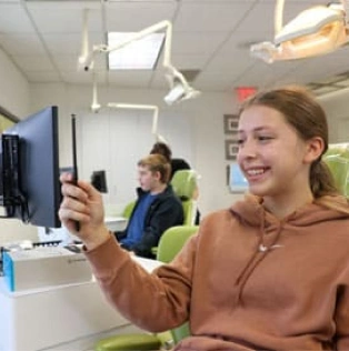 Young woman holding tablet in modern orthodontics office with colleague in background.